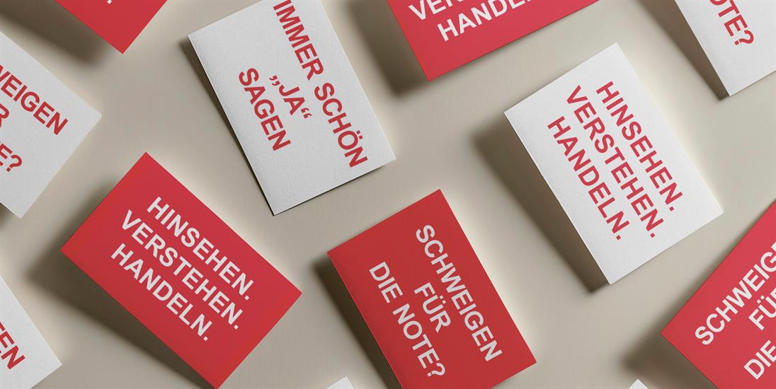 	
auf beigen Hintergrund sind mehre Postkarten abgebildet. Teils rot mit weißer Aufschrift und teils weiß mit roter Aufschrift. Auf den Postkarten stehen folgende Sprüche: „Immer schön „Ja“ sagen“, „Schweigen für die Note“ und „Hinsehen. verstehen. Handeln“